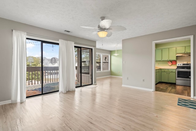 unfurnished living room featuring light wood finished floors, baseboards, visible vents, and a textured ceiling