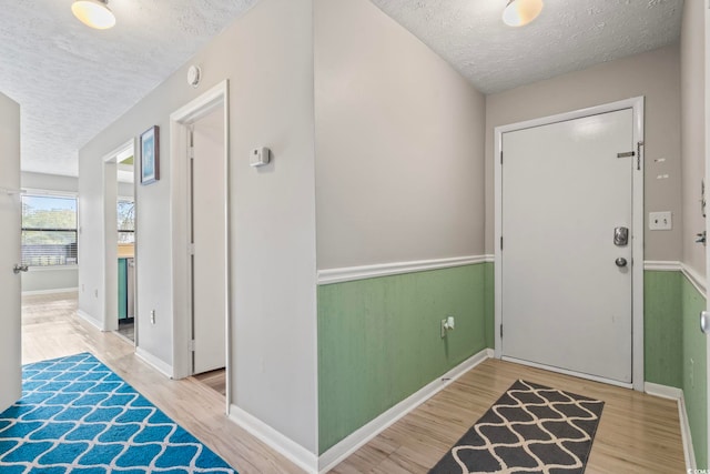 entrance foyer featuring a textured ceiling, wood finished floors, and baseboards