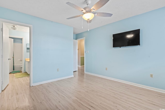 unfurnished bedroom with light wood-style flooring, connected bathroom, ceiling fan, a textured ceiling, and baseboards