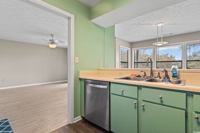 kitchen with a sink, a textured ceiling, green cabinetry, and stainless steel dishwasher