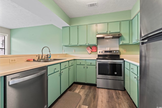 310 5th Ave N Unit 206, Surfside Beach, SC 29575 - kitchen featuring appliances with stainless steel finishes, under cabinet range hood, a sink, a textured ceiling, and dark wood-style floors