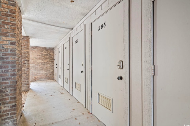 310 5th Ave N Unit 206, Surfside Beach, SC 29575 - hallway featuring brick wall and a textured ceiling