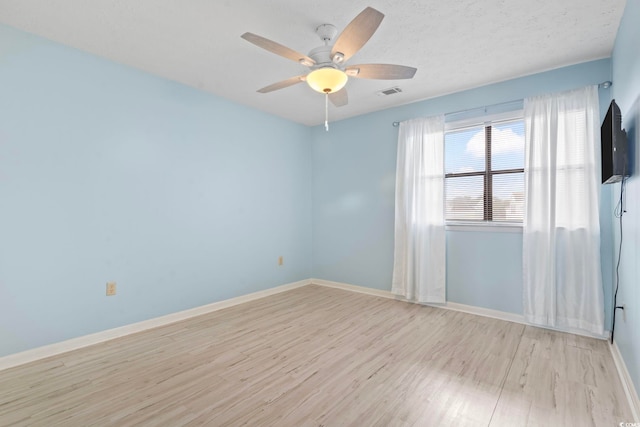 unfurnished room with light wood-type flooring, baseboards, visible vents, and ceiling fan