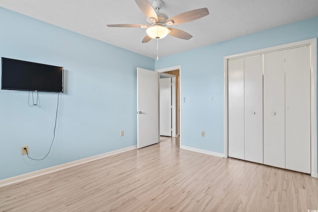 unfurnished bedroom with a ceiling fan, a closet, light wood-style flooring, and baseboards