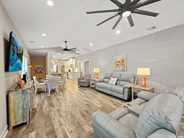 living area with vaulted ceiling, light wood-type flooring, visible vents, and recessed lighting