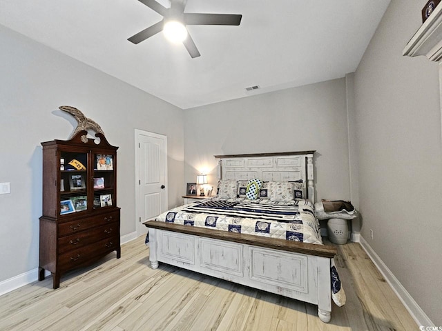 bedroom featuring light wood-type flooring, visible vents, baseboards, and ceiling fan