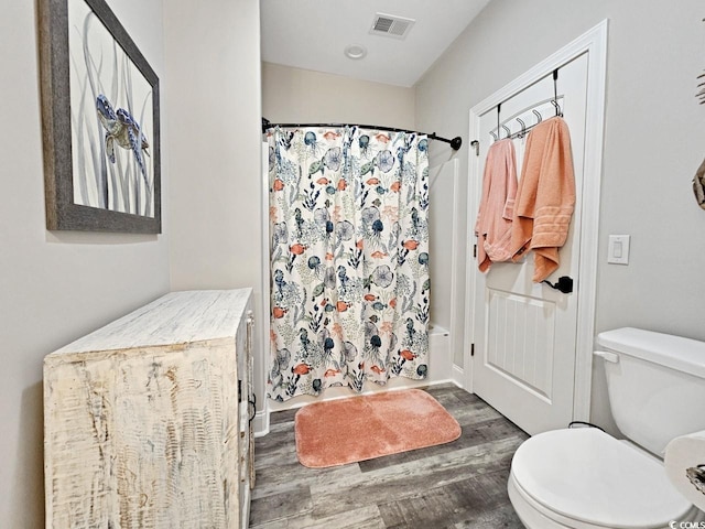 full bathroom featuring toilet, curtained shower, wood finished floors, and visible vents