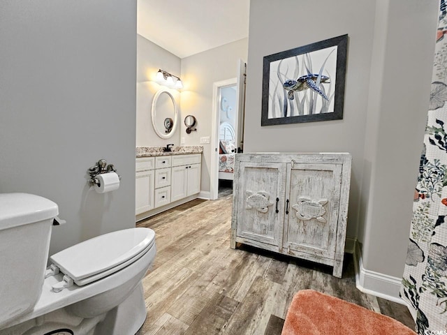 bathroom featuring vanity, wood finished floors, toilet, and baseboards