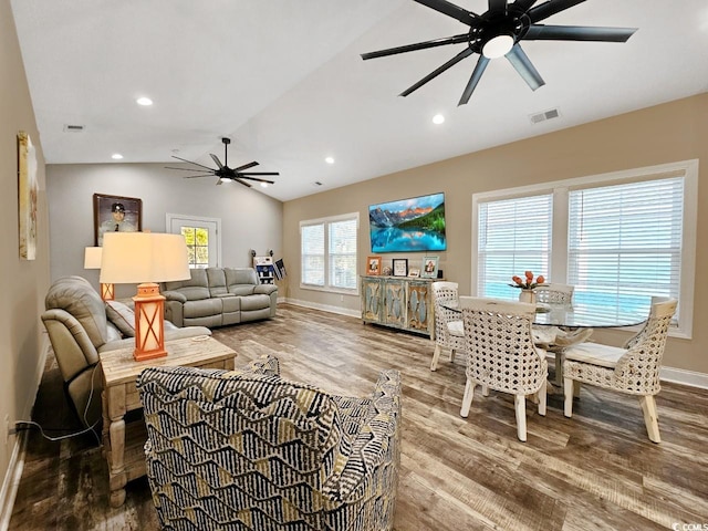 living area featuring ceiling fan, wood finished floors, visible vents, baseboards, and vaulted ceiling