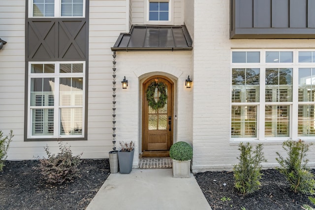 doorway to property with a standing seam roof, metal roof, and brick siding