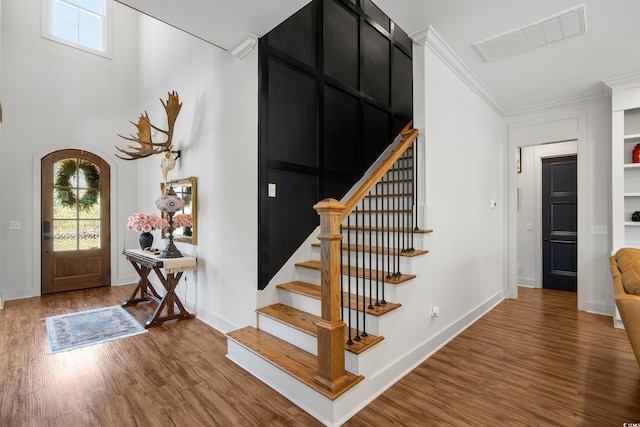 entryway featuring stairs, arched walkways, visible vents, and wood finished floors