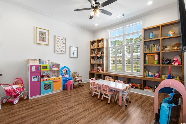 recreation room featuring ceiling fan, wood finished floors, visible vents, baseboards, and crown molding