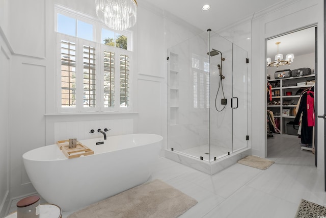 full bathroom with plenty of natural light, a freestanding bath, a decorative wall, and a notable chandelier