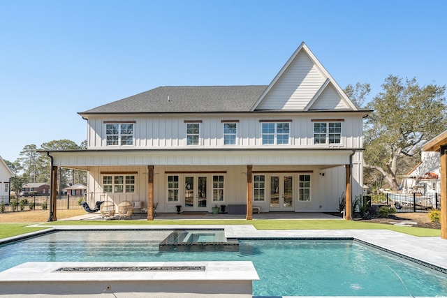 back of house featuring fence, a pool with connected hot tub, french doors, board and batten siding, and a patio area