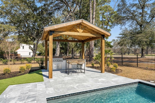 exterior space featuring an outdoor kitchen, fence private yard, a pool, a gazebo, and a patio area