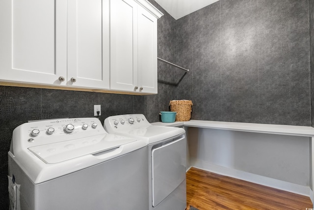 washroom with cabinet space, wood finished floors, and washing machine and clothes dryer