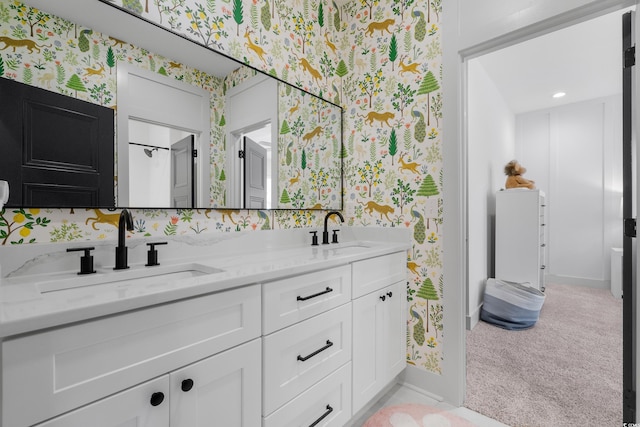 full bathroom featuring double vanity, wallpapered walls, and a sink