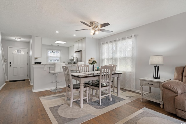 dining room featuring baseboards, a textured ceiling, and hardwood / wood-style flooring