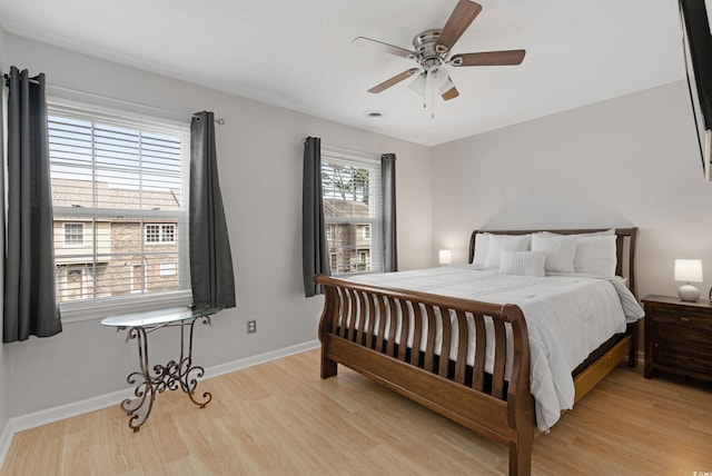 bedroom with light wood-style flooring, visible vents, baseboards, and ceiling fan