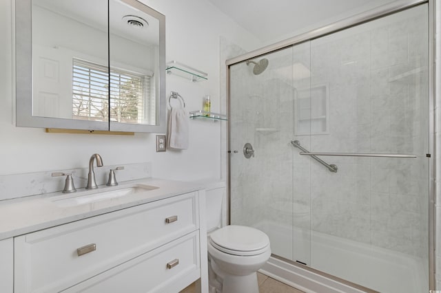 bathroom with visible vents, a shower stall, toilet, and vanity