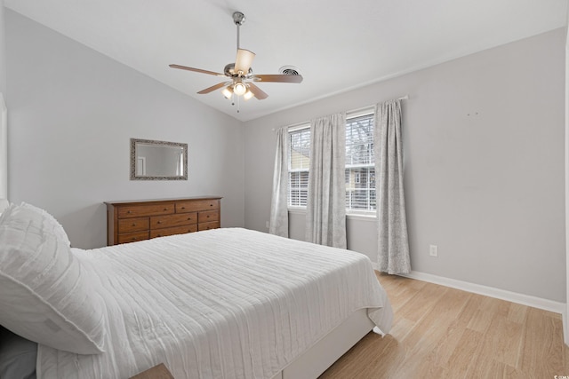 bedroom with a ceiling fan, vaulted ceiling, light wood-style floors, and baseboards