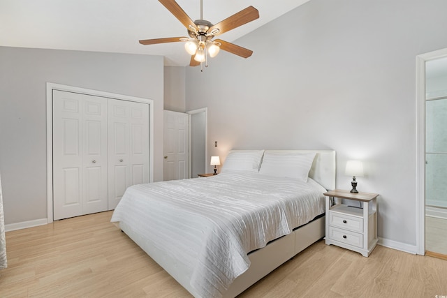 bedroom featuring a closet, baseboards, vaulted ceiling, and light wood finished floors