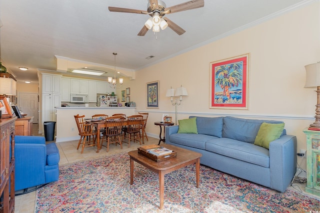 living room with ceiling fan with notable chandelier, ornamental molding, baseboards, and light tile patterned flooring