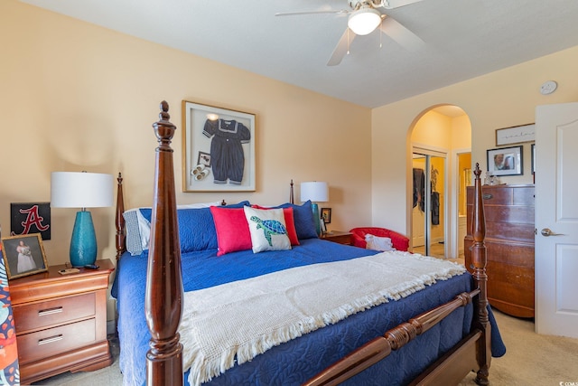 carpeted bedroom featuring arched walkways, a closet, and a ceiling fan