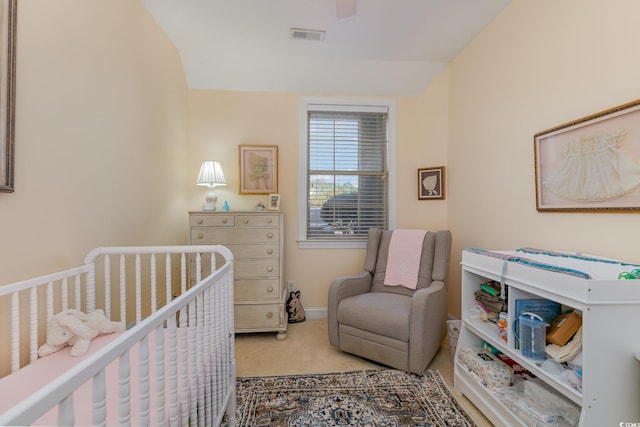 carpeted bedroom with a nursery area, baseboards, visible vents, and a ceiling fan