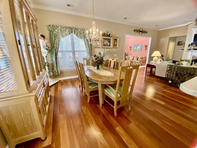 dining area with an inviting chandelier, crown molding, visible vents, and wood finished floors