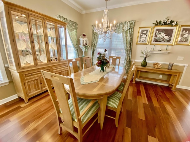 dining area featuring light wood-style floors, baseboards, ornamental molding, and an inviting chandelier