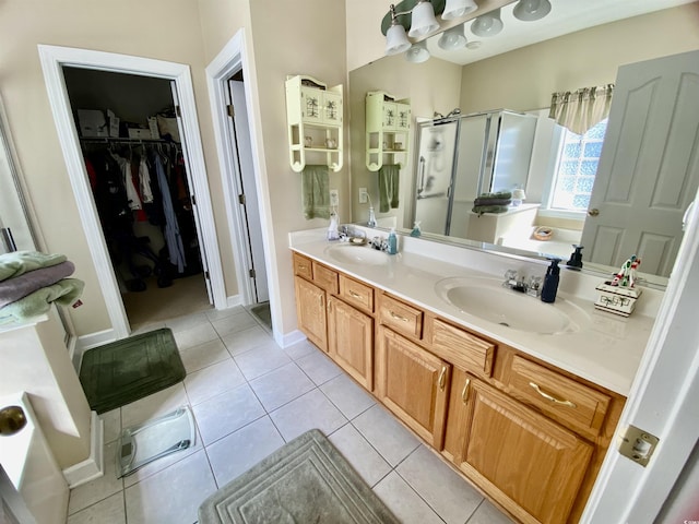 full bathroom featuring double vanity, a shower stall, a sink, and tile patterned floors