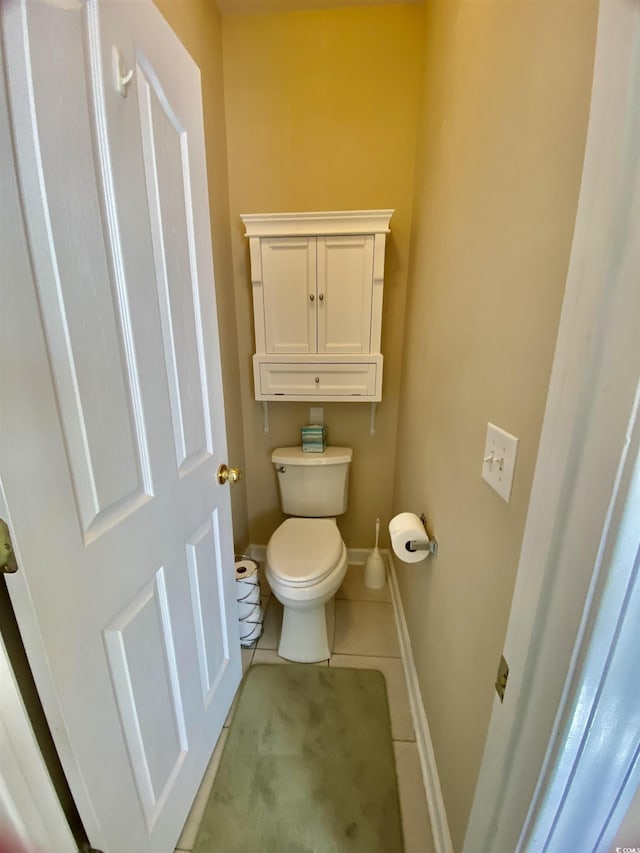 bathroom with toilet, baseboards, and tile patterned floors