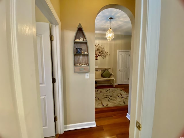 hallway with arched walkways, wood finished floors, and baseboards