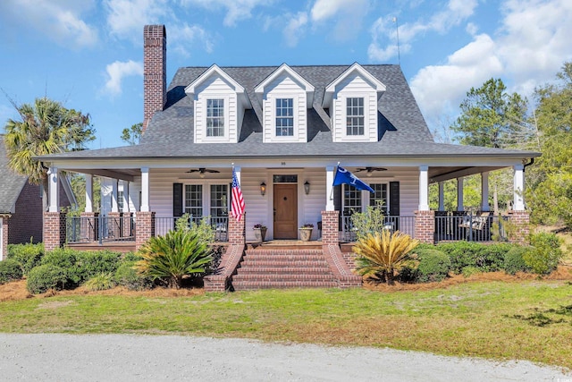 view of front facade with ceiling fan, a chimney, a porch, and a front yard