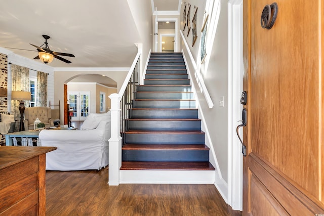 staircase with ornamental molding, arched walkways, ceiling fan, and wood finished floors