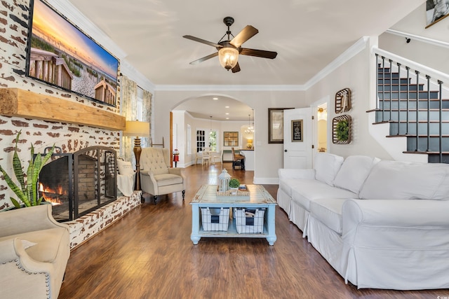 living room featuring arched walkways, ornamental molding, a brick fireplace, ceiling fan, and wood finished floors