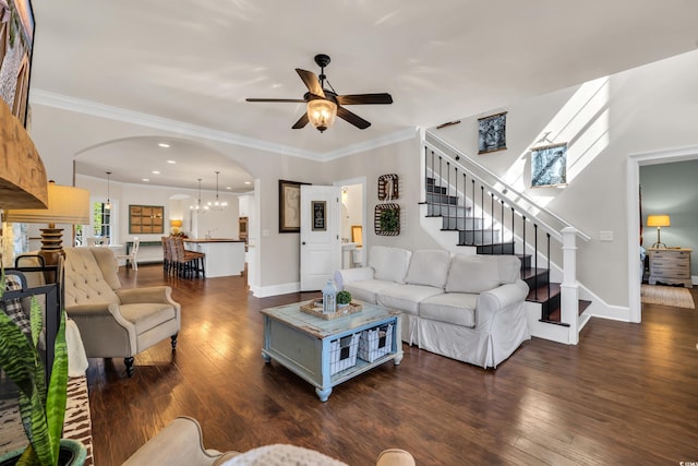 living room featuring dark wood-style floors, arched walkways, ornamental molding, and stairs