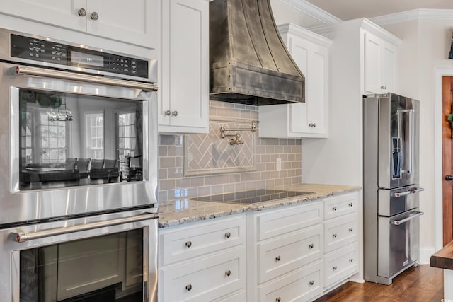 kitchen with premium range hood, white cabinets, ornamental molding, appliances with stainless steel finishes, and decorative backsplash