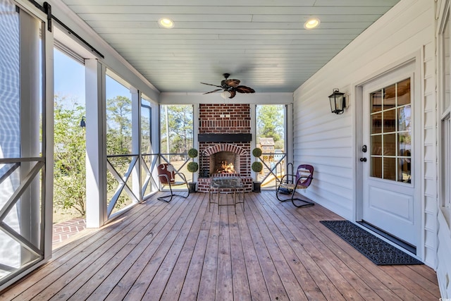 unfurnished sunroom with an outdoor brick fireplace and ceiling fan