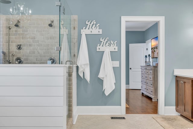 bathroom with a stall shower, baseboards, wood finished floors, crown molding, and vanity