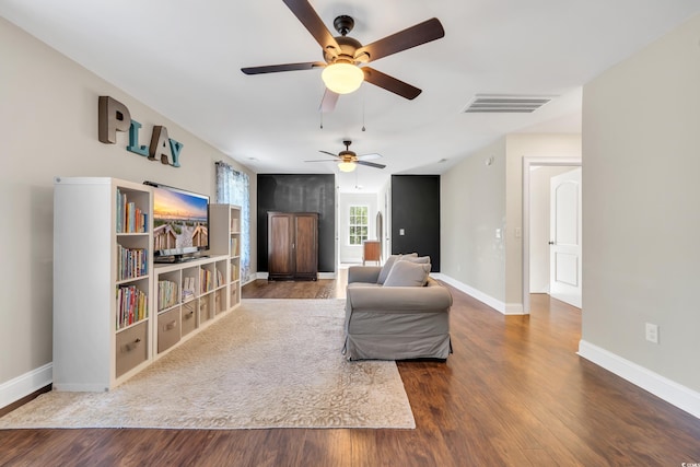 living area featuring baseboards, visible vents, and wood finished floors