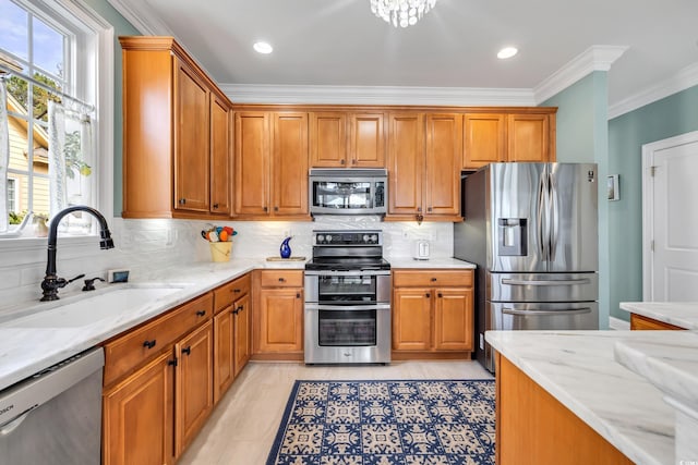 kitchen featuring appliances with stainless steel finishes, ornamental molding, a sink, light stone countertops, and backsplash