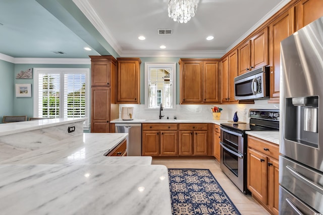 kitchen featuring light tile patterned floors, visible vents, appliances with stainless steel finishes, brown cabinets, and a sink