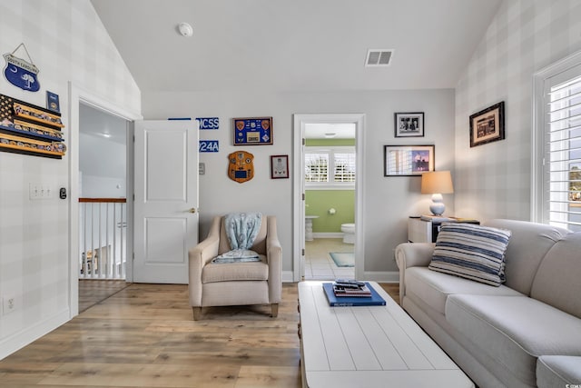 living area featuring baseboards, visible vents, vaulted ceiling, and wood finished floors