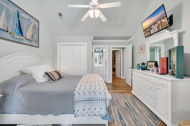 bedroom with light wood finished floors, a closet, visible vents, a ceiling fan, and vaulted ceiling