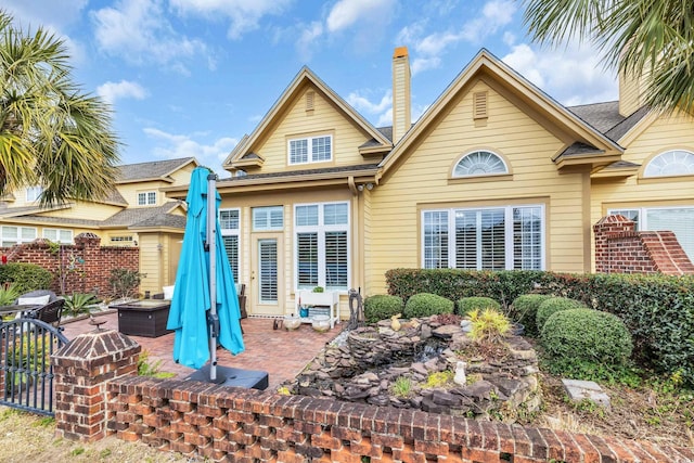 rear view of house with a patio, an outdoor fire pit, a chimney, and fence