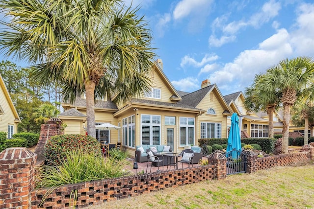 rear view of property featuring a chimney, roof with shingles, a patio, and an outdoor living space