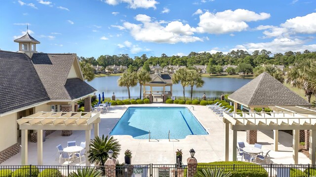 community pool with a patio, a water view, fence, and a pergola