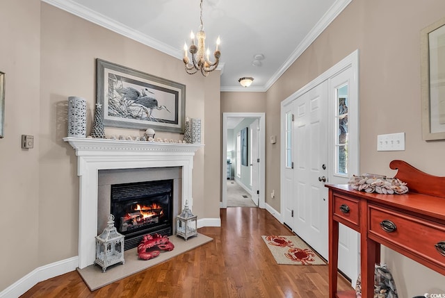 entryway with ornamental molding, a glass covered fireplace, a chandelier, and wood finished floors